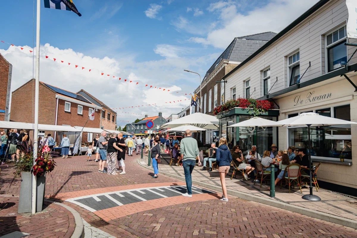 Een levendige straat in Philippine met terrassen, mensen die wandelen en dineren en een blauwe lucht met wolken.