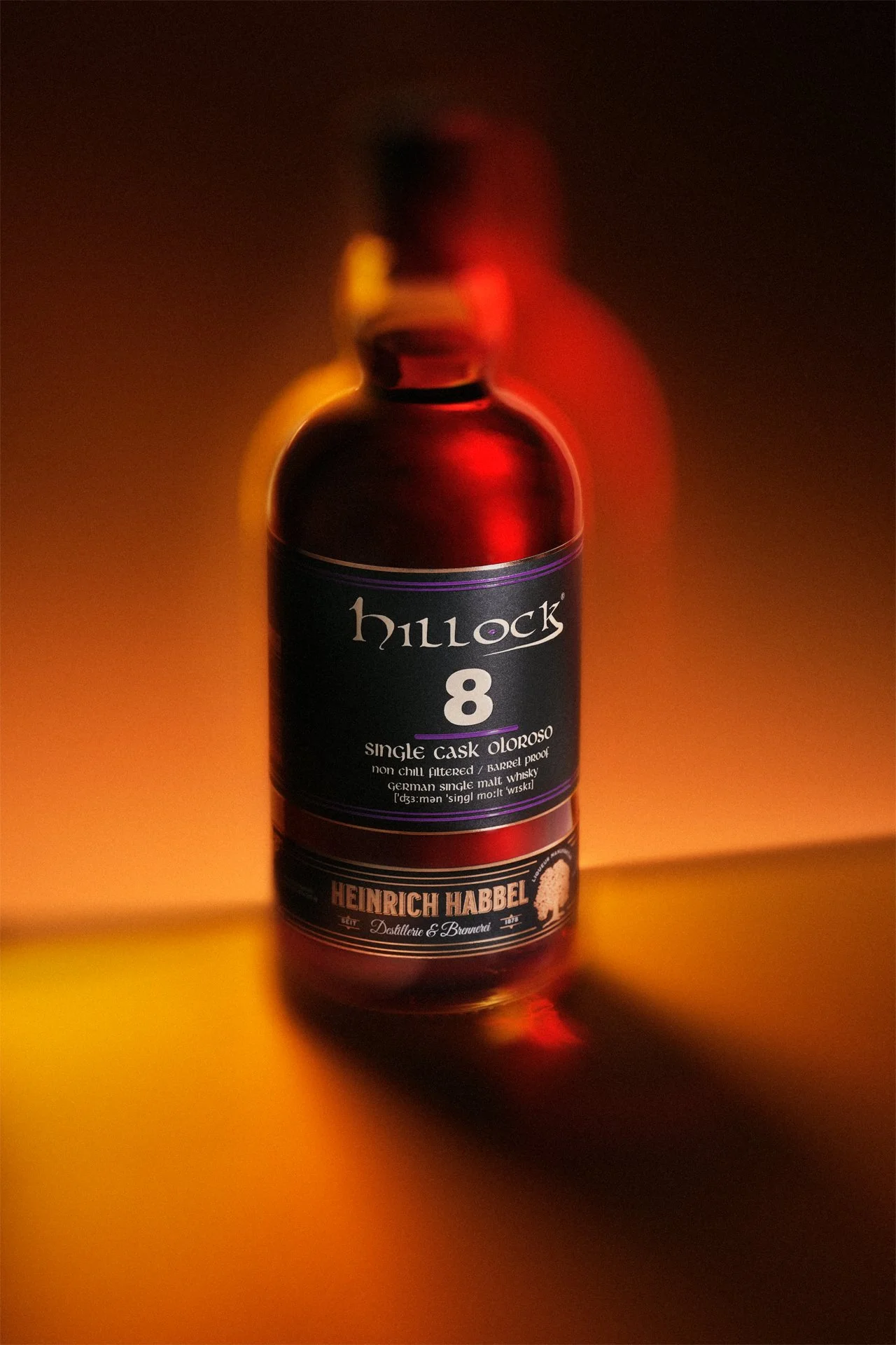 Eine Flasche Hillock 8 Single Cask Oloroso Whisky, hergestellt von Heinrich Habbel. Der Whisky hat eine dunkelbraune Farbe und die Flasche ist in warmem Licht beleuchtet.
