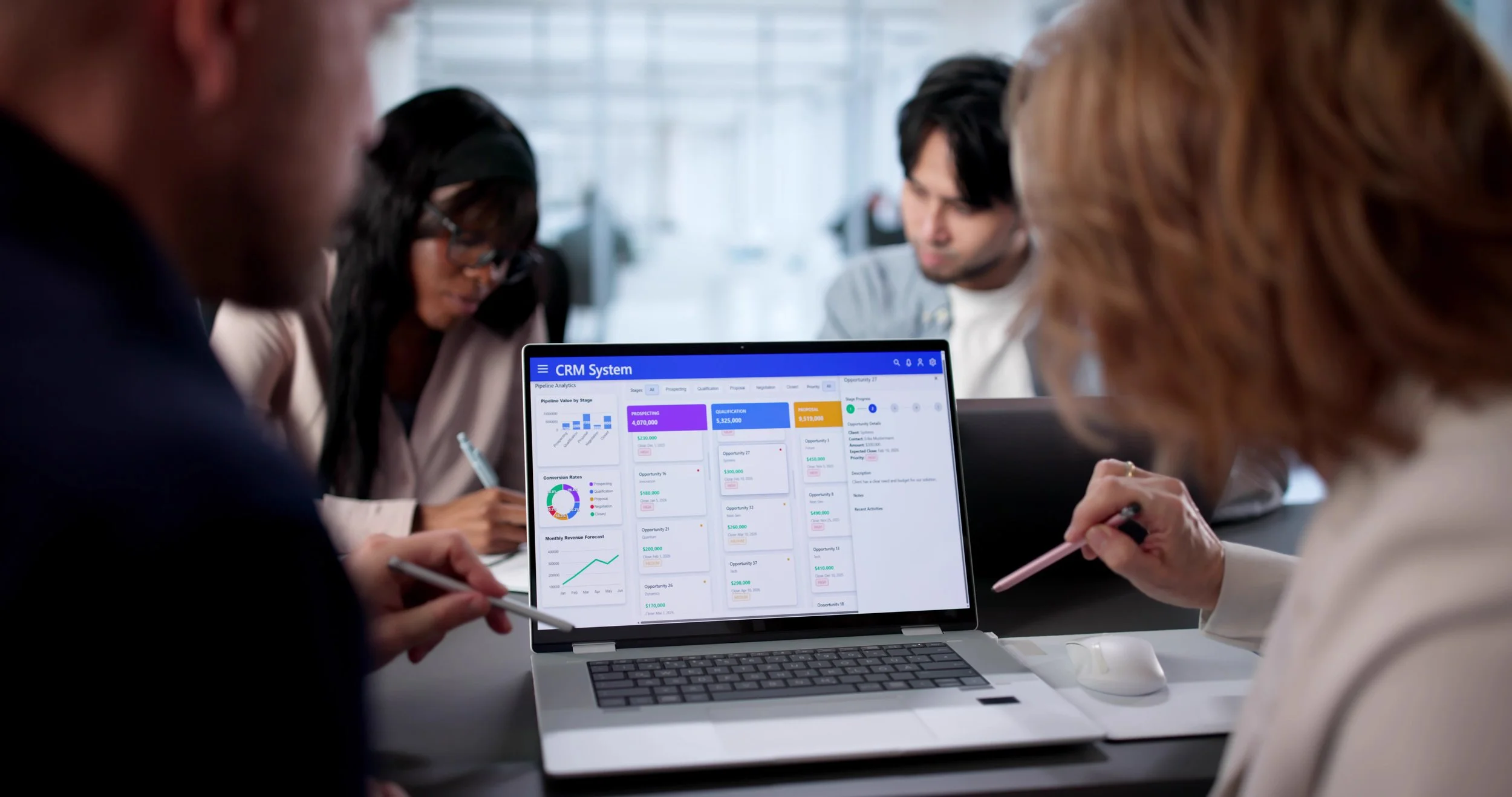 Business meeting with people looking at a laptop displaying a CRM system dashboard with charts and data.