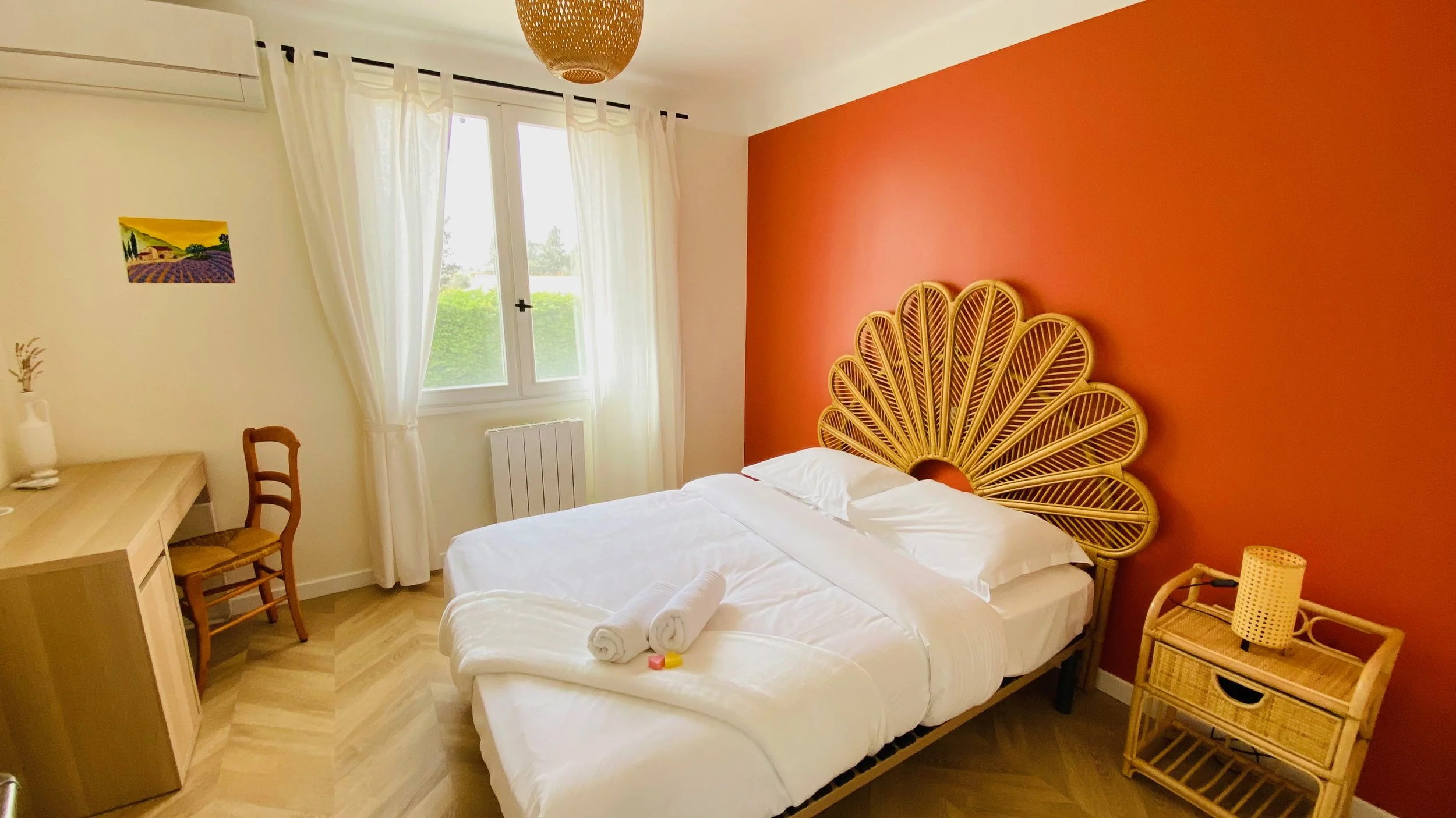 Bright bedroom with rattan headboard and red accent wall at Villa Magali Arles