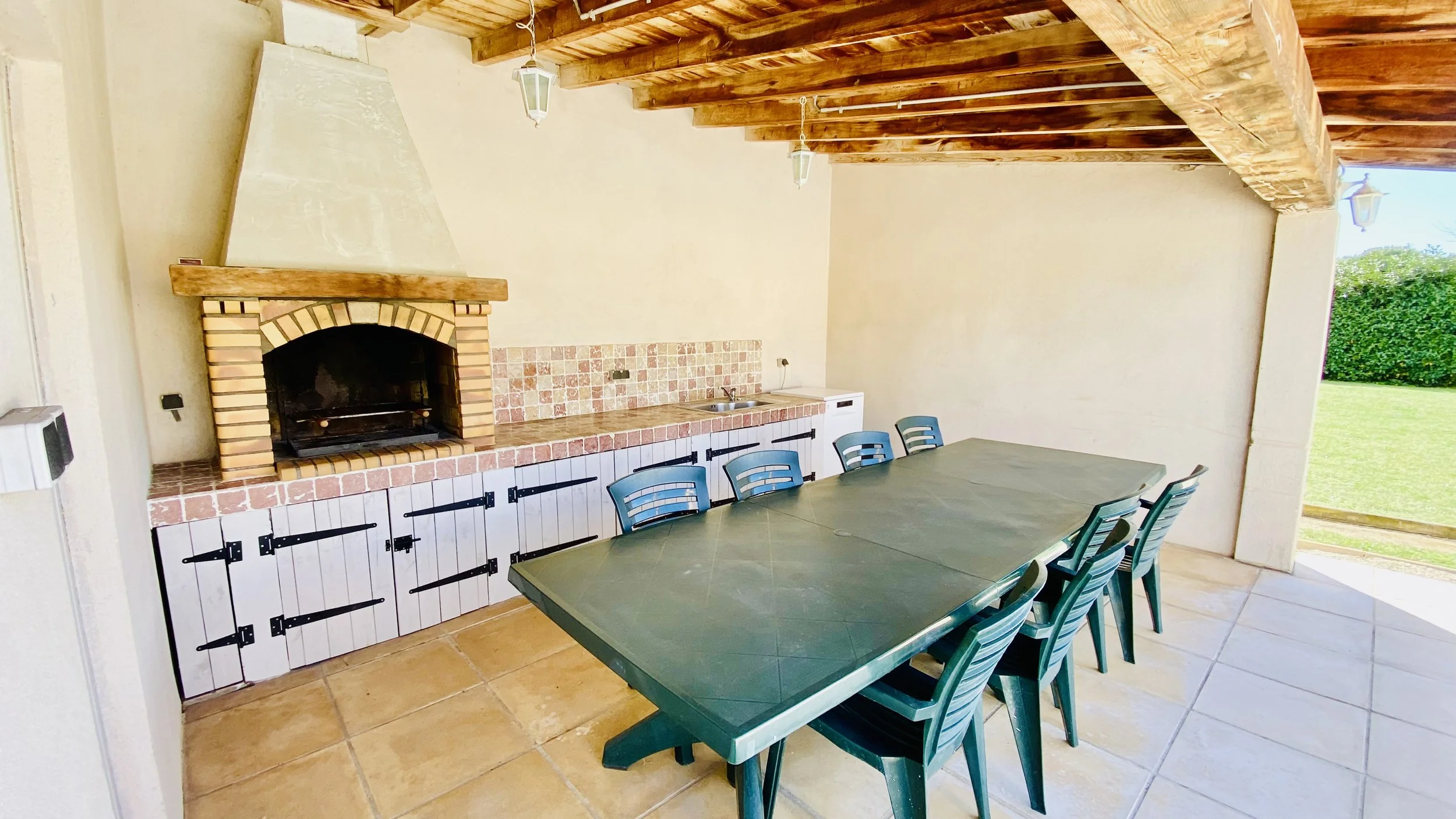Covered terrace with barbecue and large dining table at Villa Magali Arles