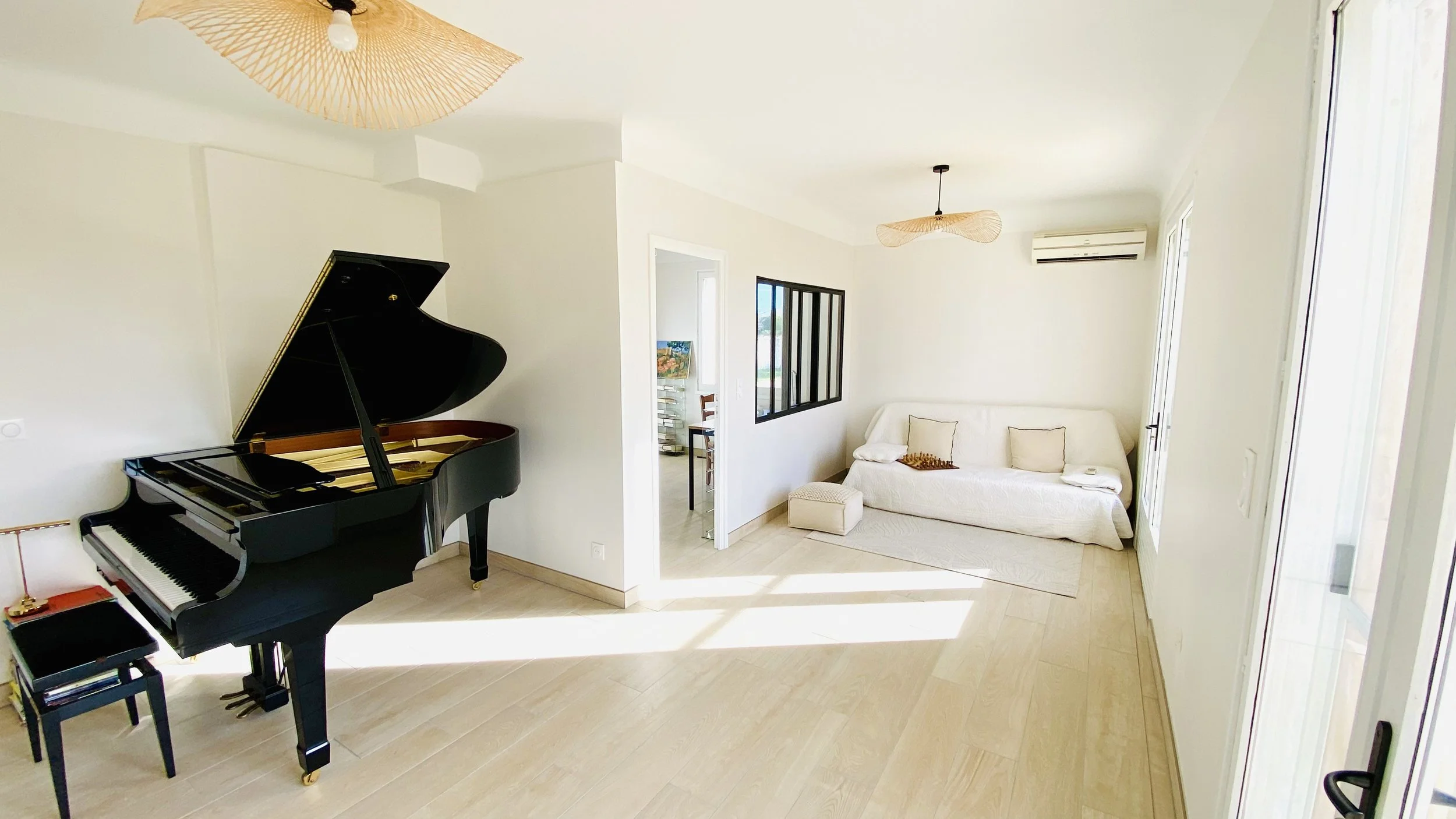Bright living room with grand piano and sofa seating area at Villa Magali Arles in Provence