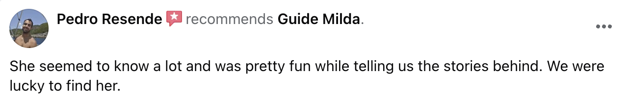 A woman with short blonde hair wearing a black shirt, sitting outdoors near trees.