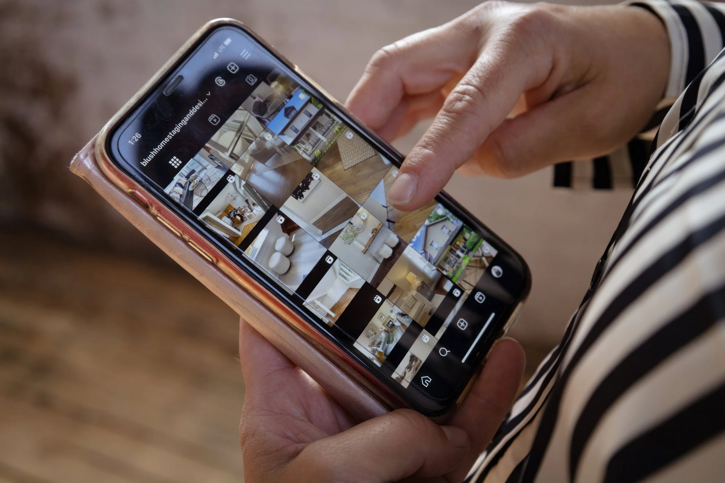 A person holding a smartphone and browsing through a grid of interior design or real estate photos.