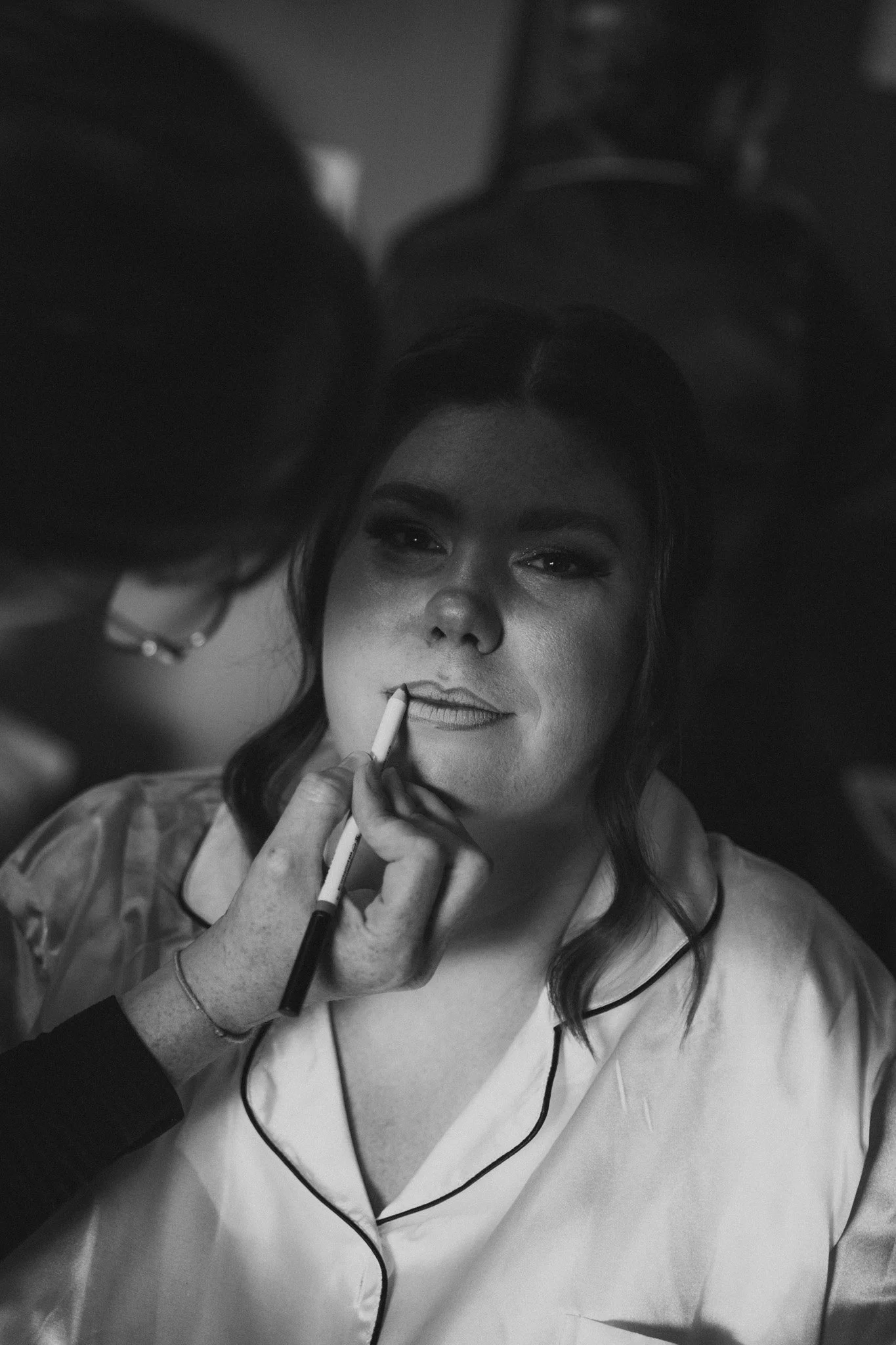 A woman getting makeup applied by a makeup artist in a professional setting.
