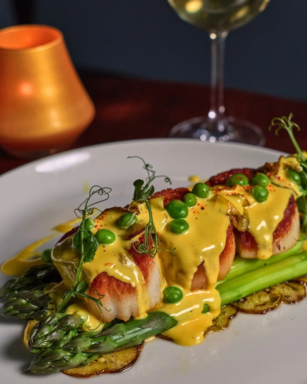 Dinner is served: Jumbo Scallops with asparagus, green tomatoes, english peas, and uni b&eacute;arnaise.

📸 @briansamuelsphotography