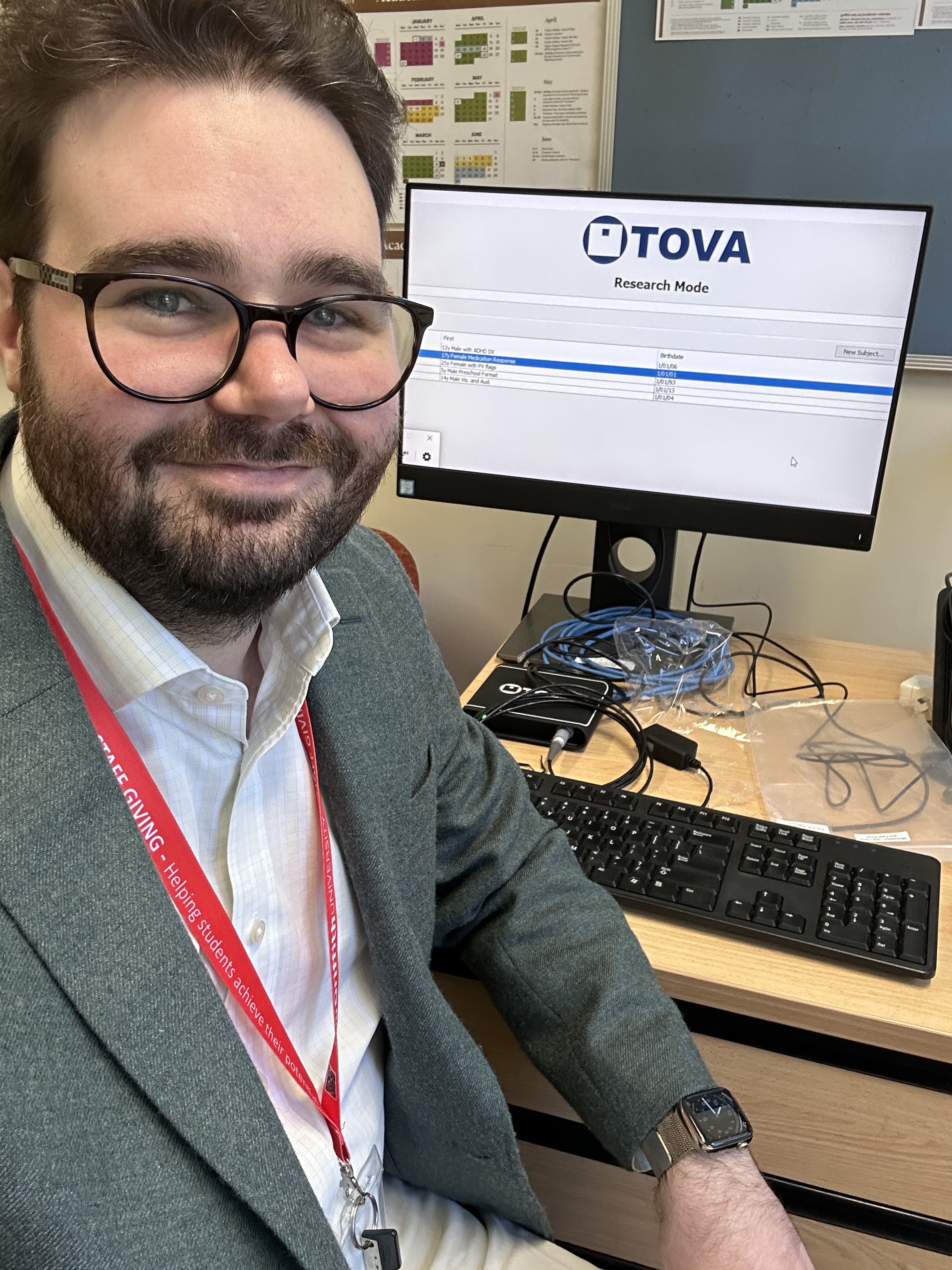 Dr Sullivan sitting at a desk with a computer showing the TOVA test