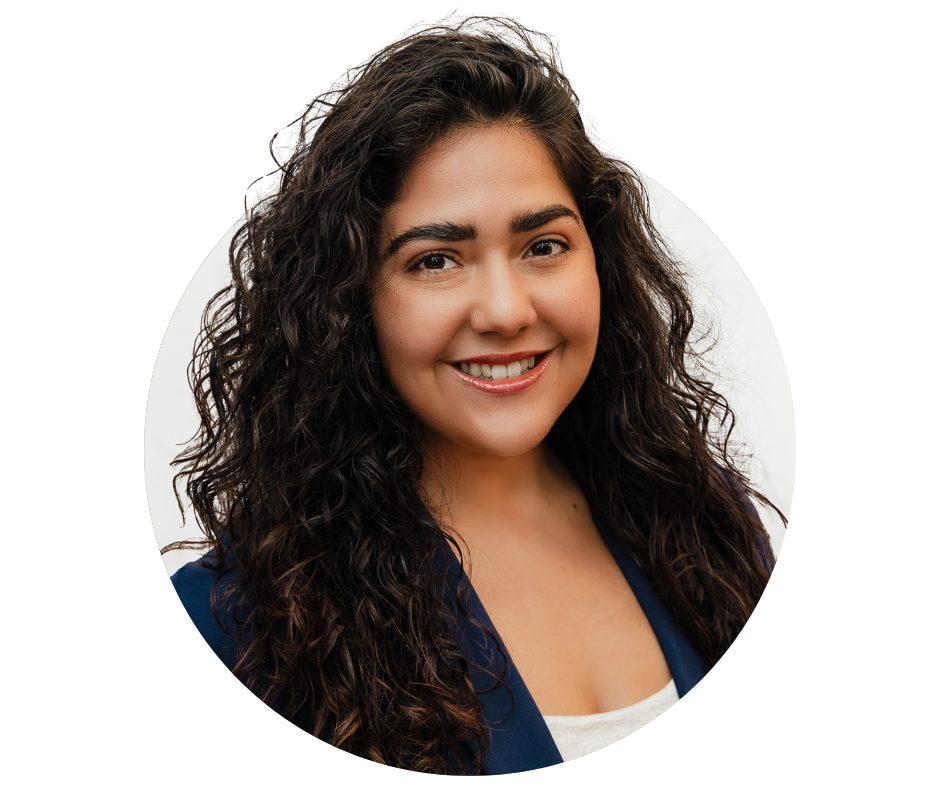 Portrait of a woman with long curly dark hair smiling at the camera, wearing a dark blazer and white top.