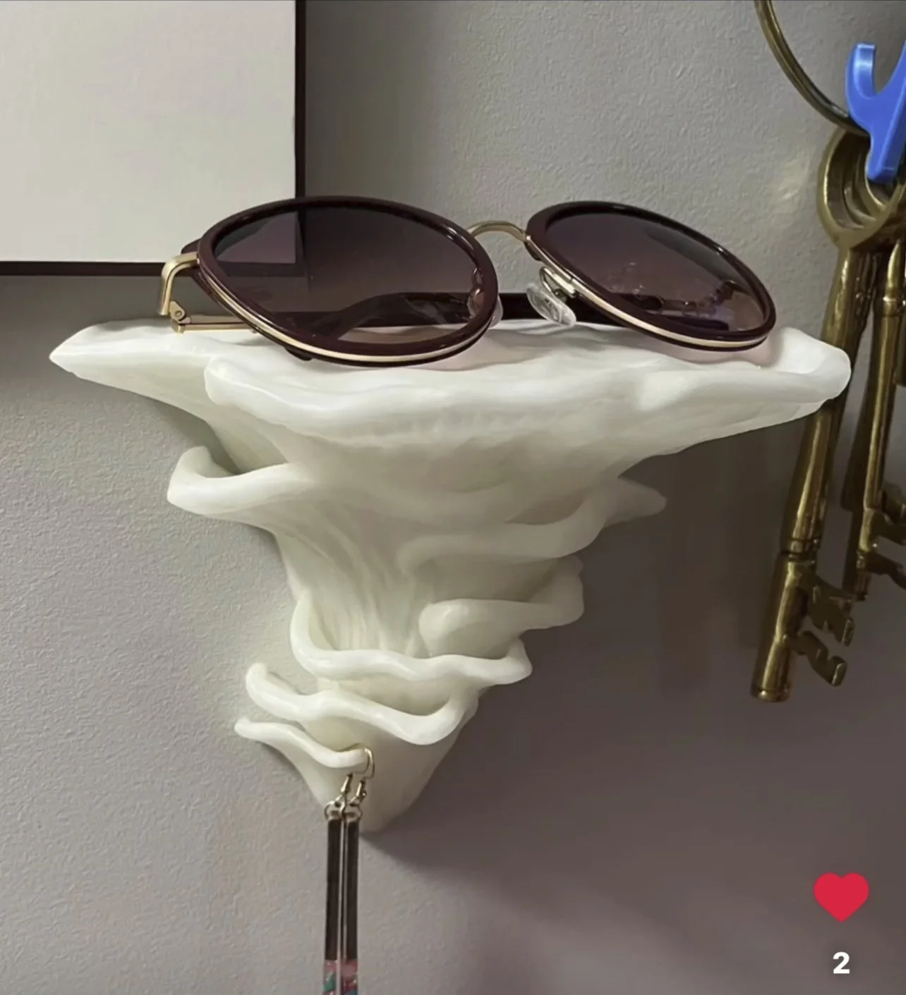 A pair of sunglasses resting on a decorative white wall-mounted sculpture shaped like a mushroom.