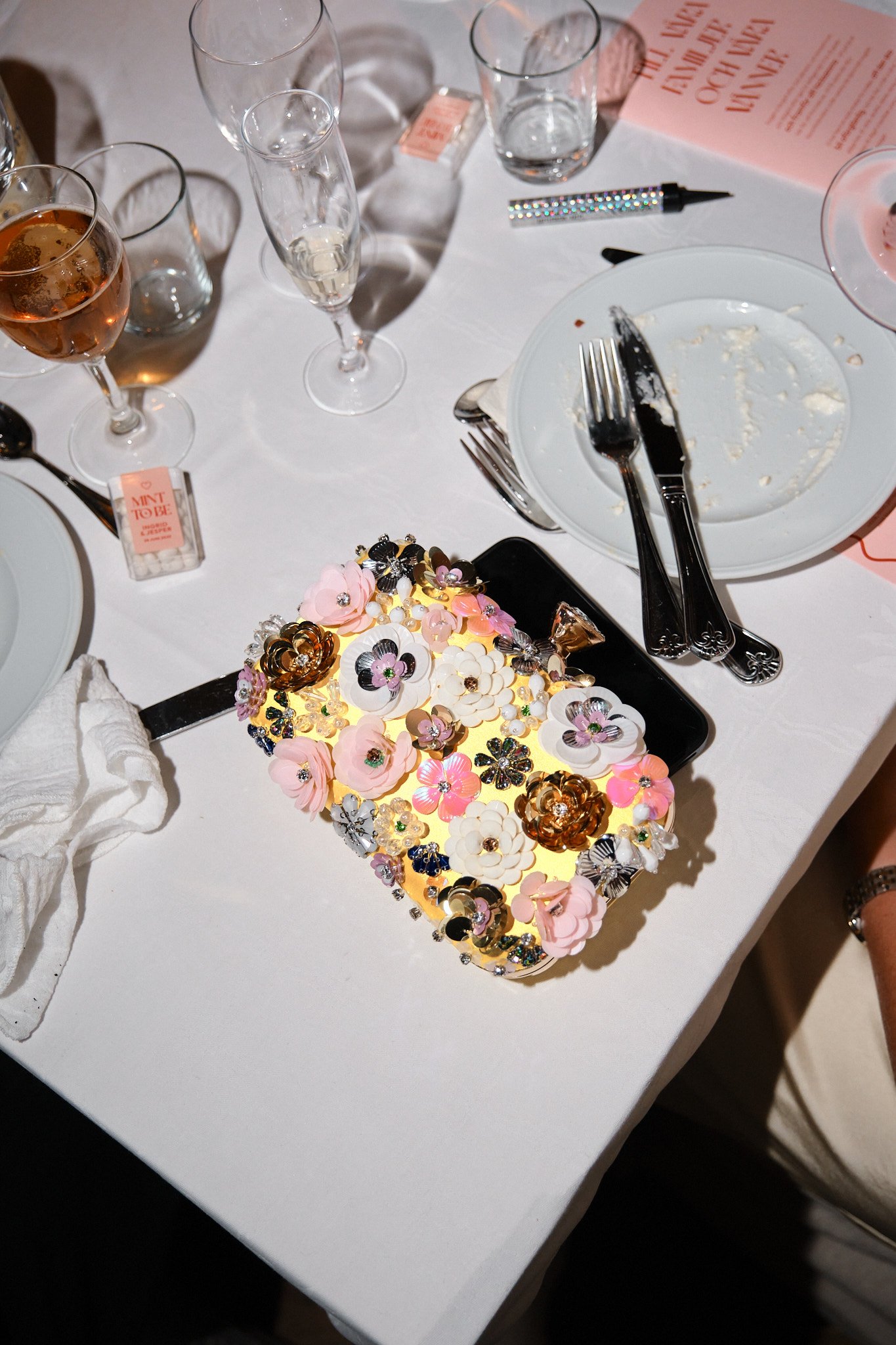 Ett bord med tomma tallrikar, tomma glas, bestick och ett pyntat telefonfodral med blommor och ljus lysande.