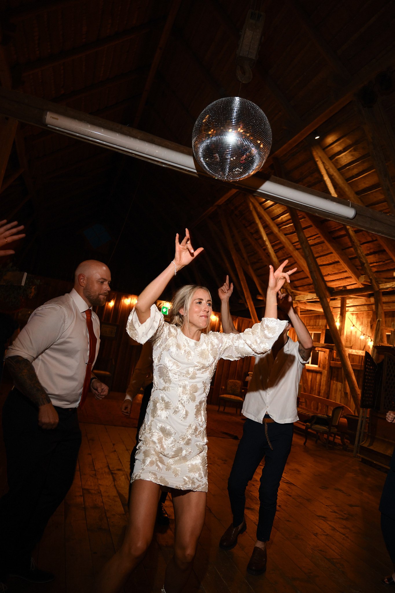 Personer dansar under en discokula i ett träbostad rum.