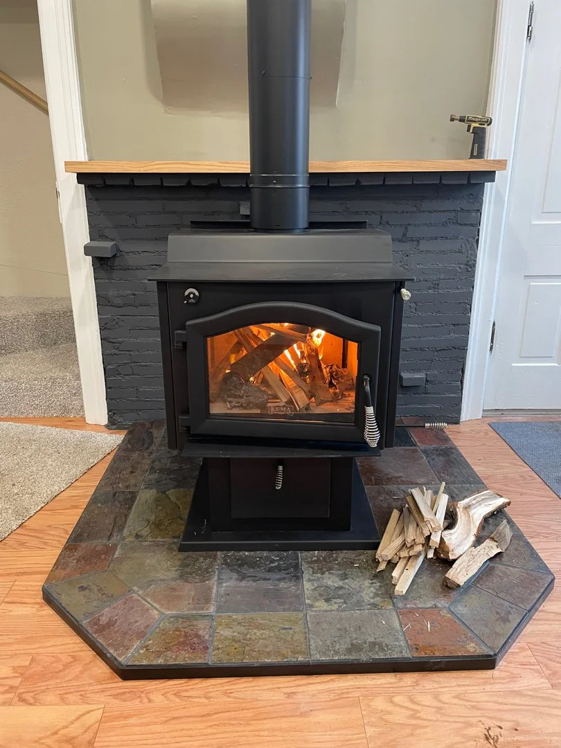 classic wood stove on stone slab and black brick surround
