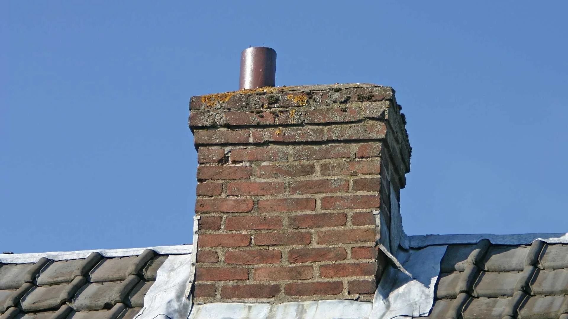 red brick chimney on top of house on a cold summer day