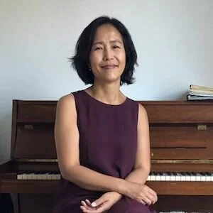 Woman sitting in front of a piano with sheet music on it.