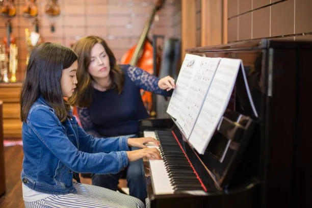 Piano student wearing blue jacket played her piano piece with her piano teacher from NUVO Music School
