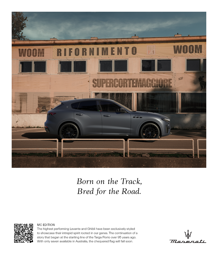 A sleek gray Maserati SUV parked on the street in front of an old, weathered building with signs in Italian and a small dog silhouette. The text below reads: "Born on the Track, Bred for the Road" with a Maserati logo.