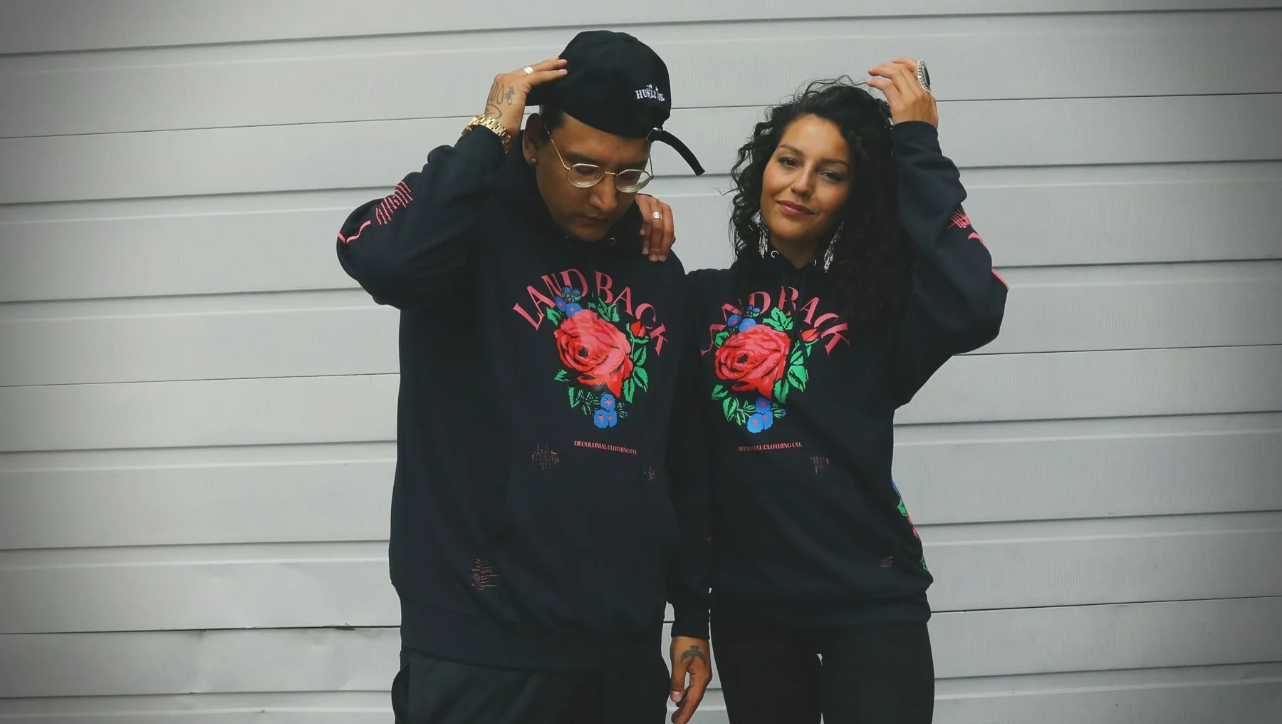 Dakota Bear and Casey Desjarlais wearing matching Land Back rose hoodies from Decolonial Clothing