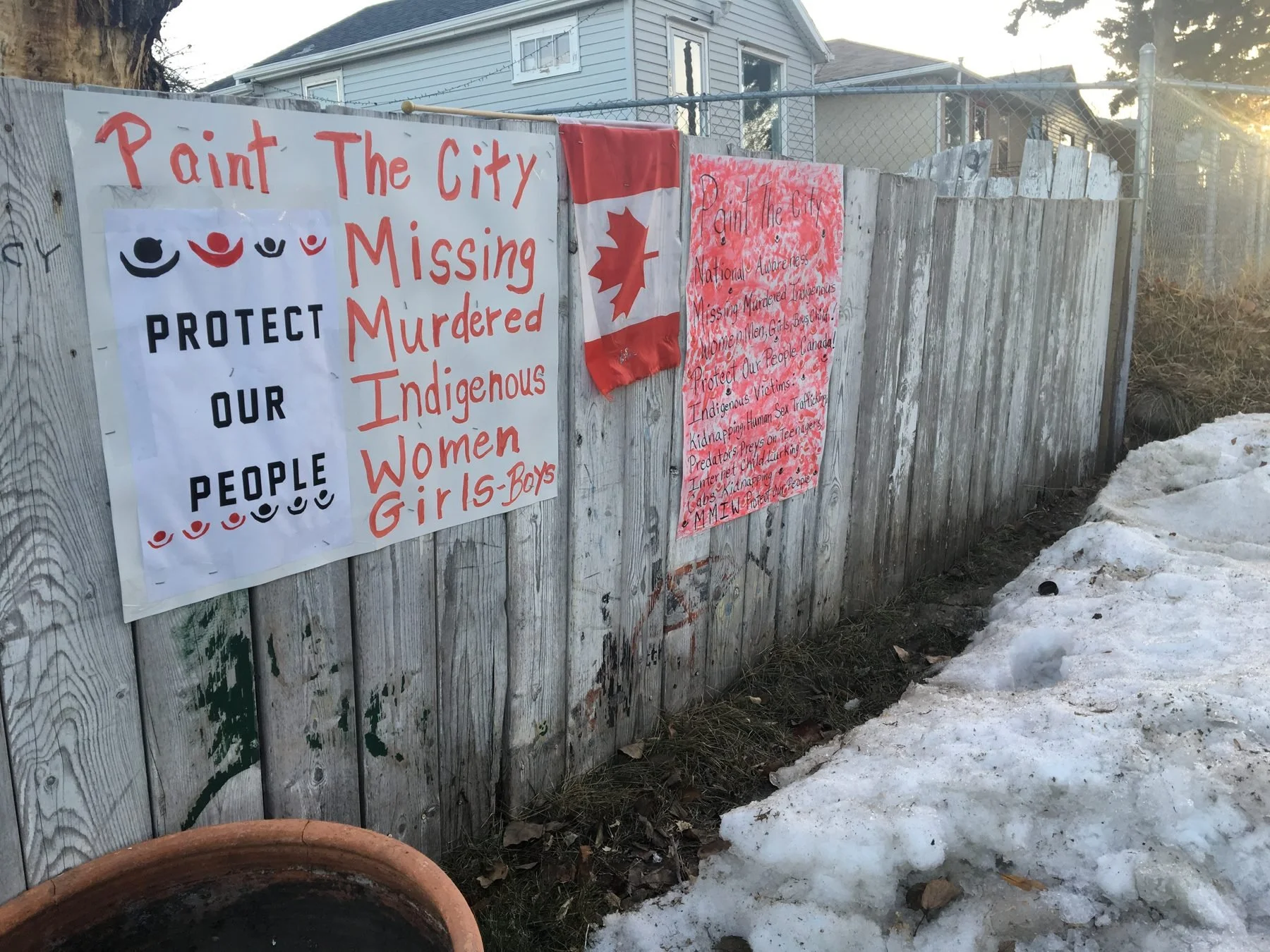 Hand-painted Protect Our People and Paint the City signs for Missing and Murdered Indigenous Women on a Saskatoon fence