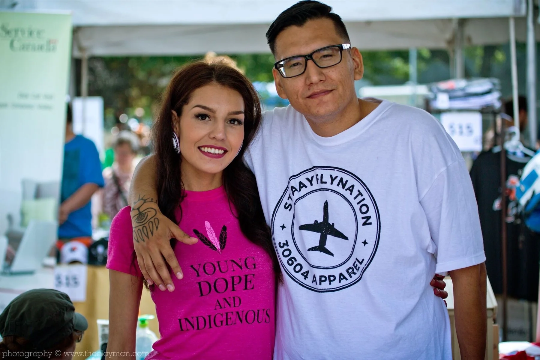 Casey Desjarlais and Dakota Bear at a market booth in their early 30604 Apparel shirts, Young Dope and Indigenous and StaayFlyNation