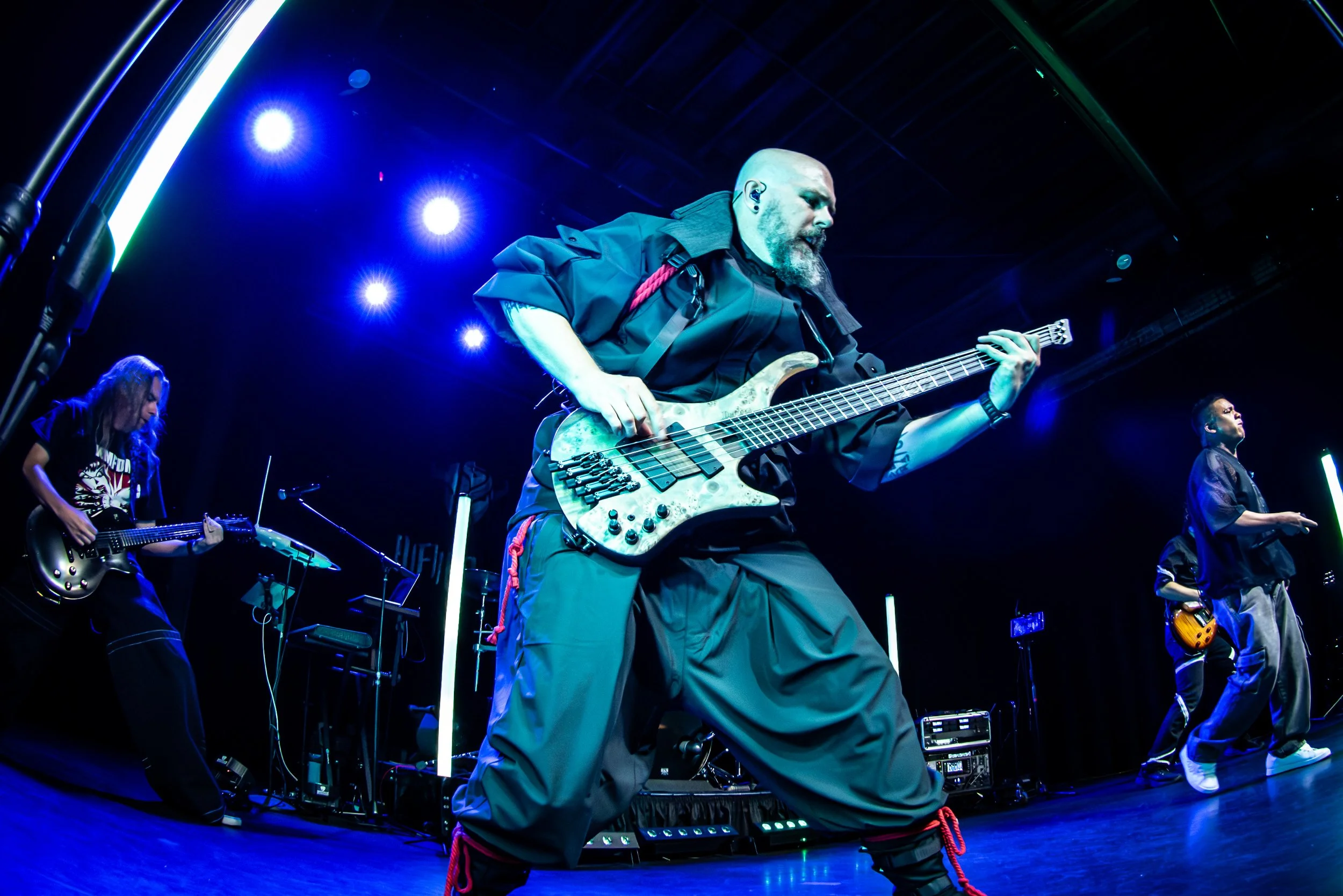 A band performing on stage with three guitarists and a bass player, illuminated by blue stage lights.