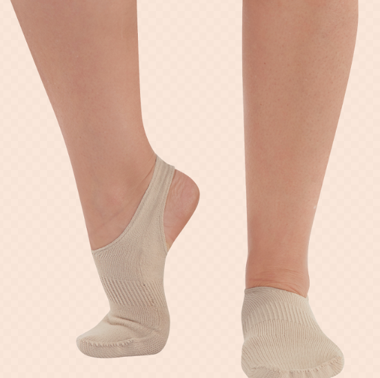 Two feet wearing beige no-show socks on a checkered background.