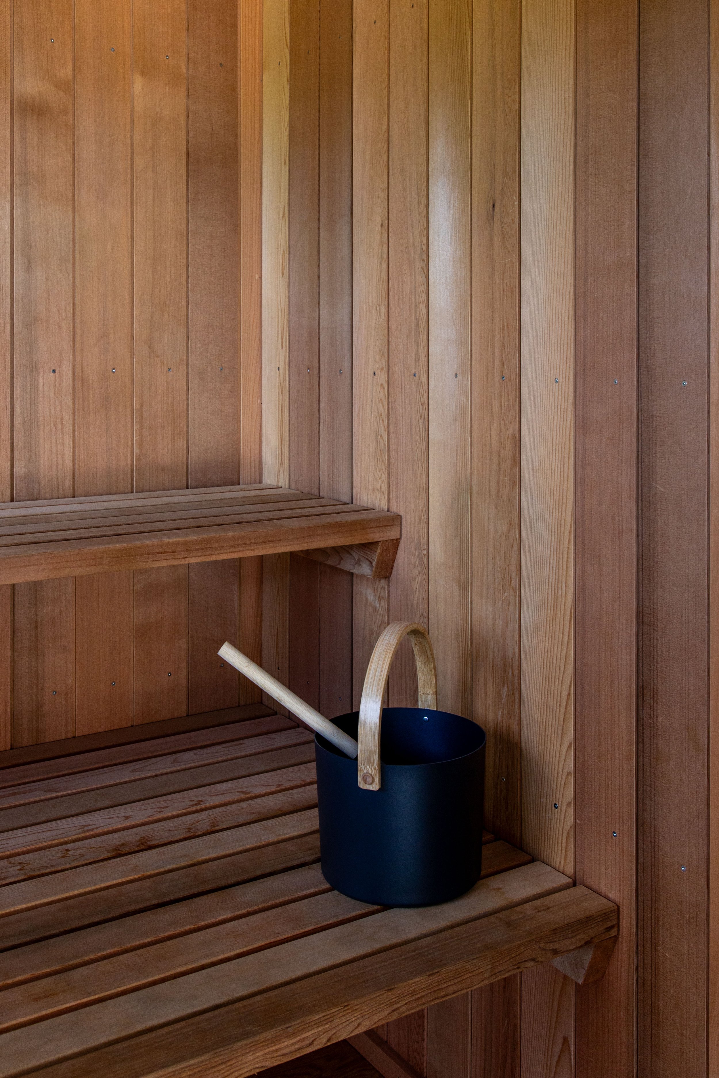 Cedar sauna interior with Harvia sauna accessories, bucket and ladle to add water to sauna rocks and produce steam