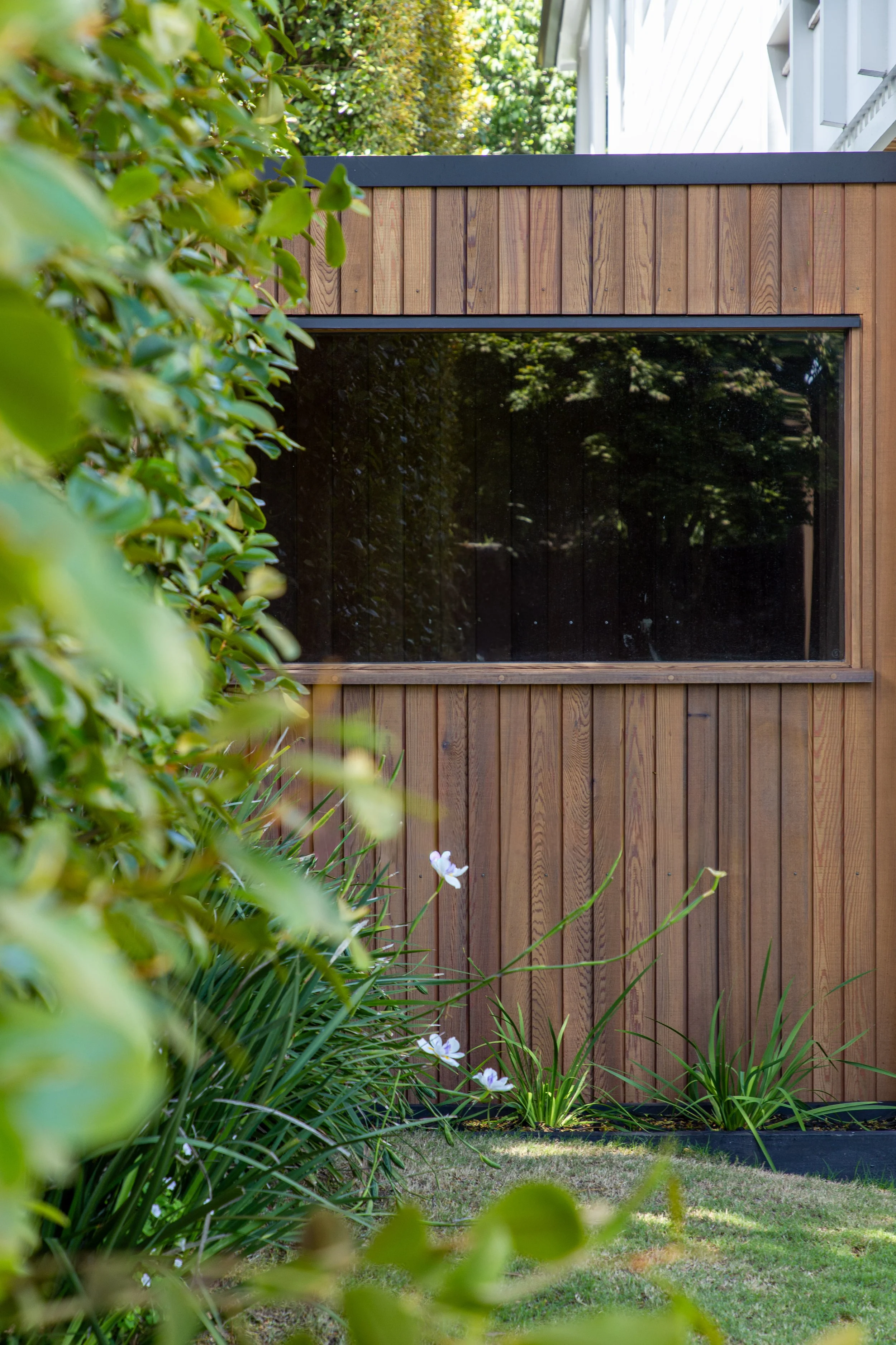 Outdoor sauna in mount eden garden, with large window overlooking the garden and cedar cladding