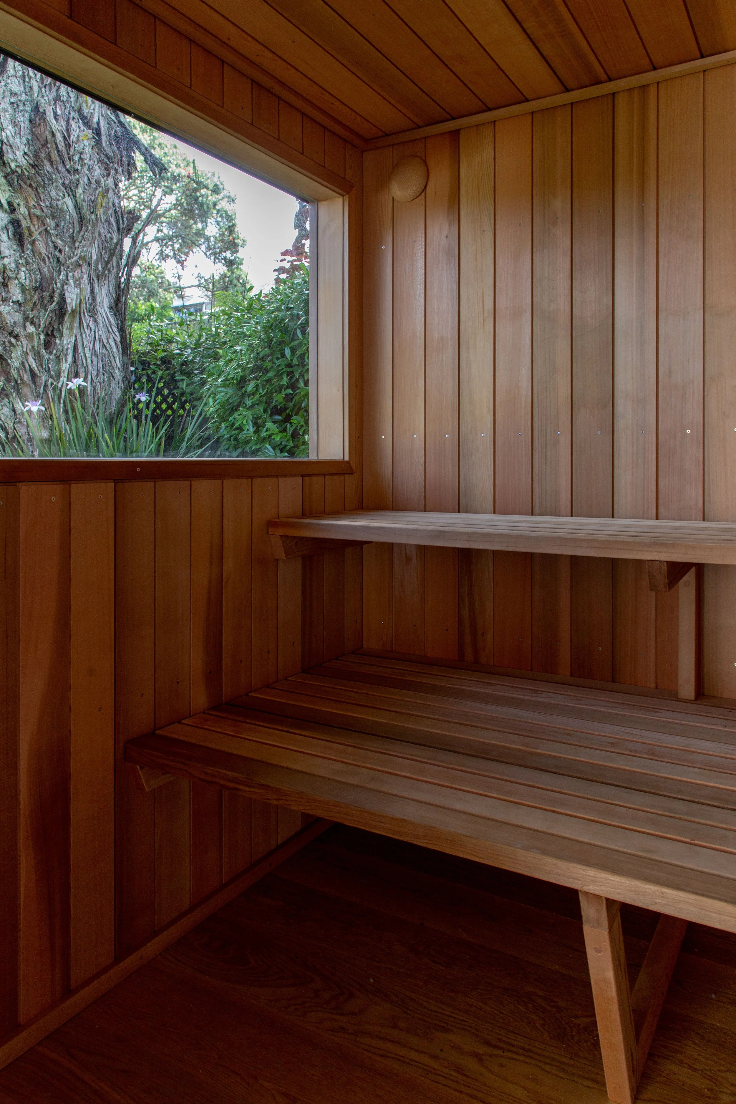 Cedar lined sauna interior with cedar double tiered bench seats overlooking established mount eden garden