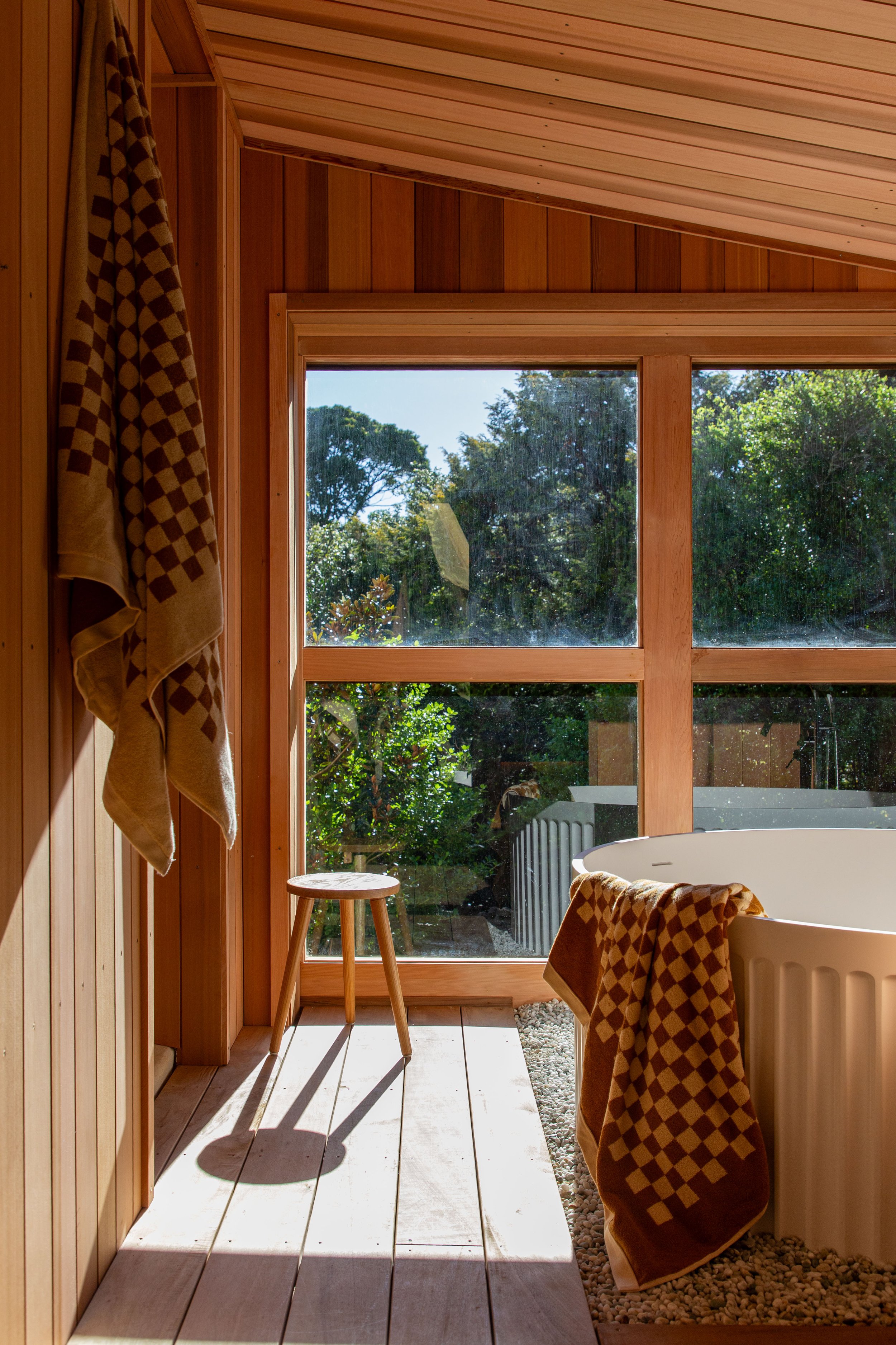 A custom built cedar lined traditional wood fired sauna, featuring a Roaring Meg wood burning sauna heater and stone bath with a large picture window overlooking the back garden.