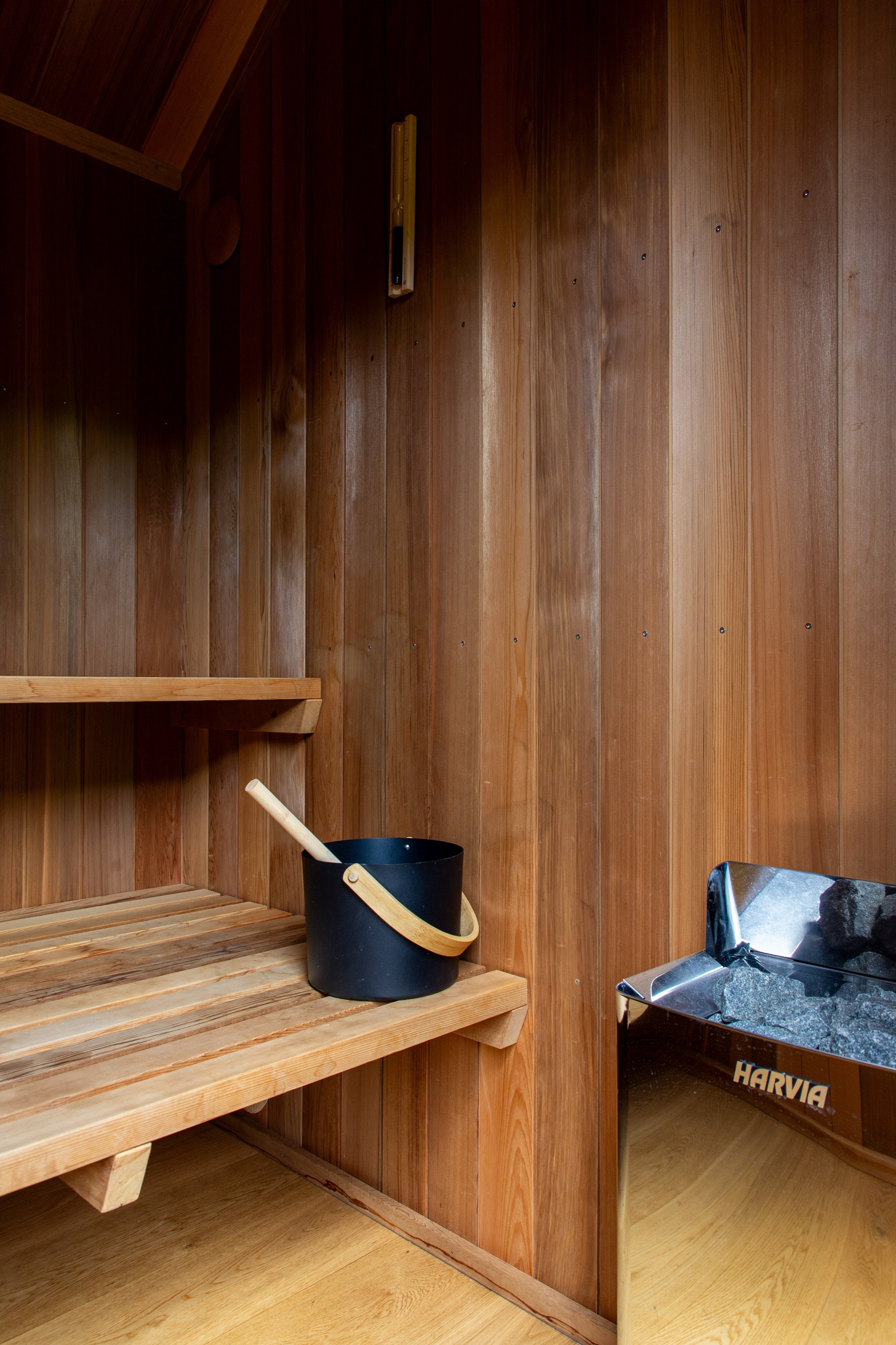 Cedar lined sauna interior, with double tier solid cedar benches and Harvia electric sauna heater