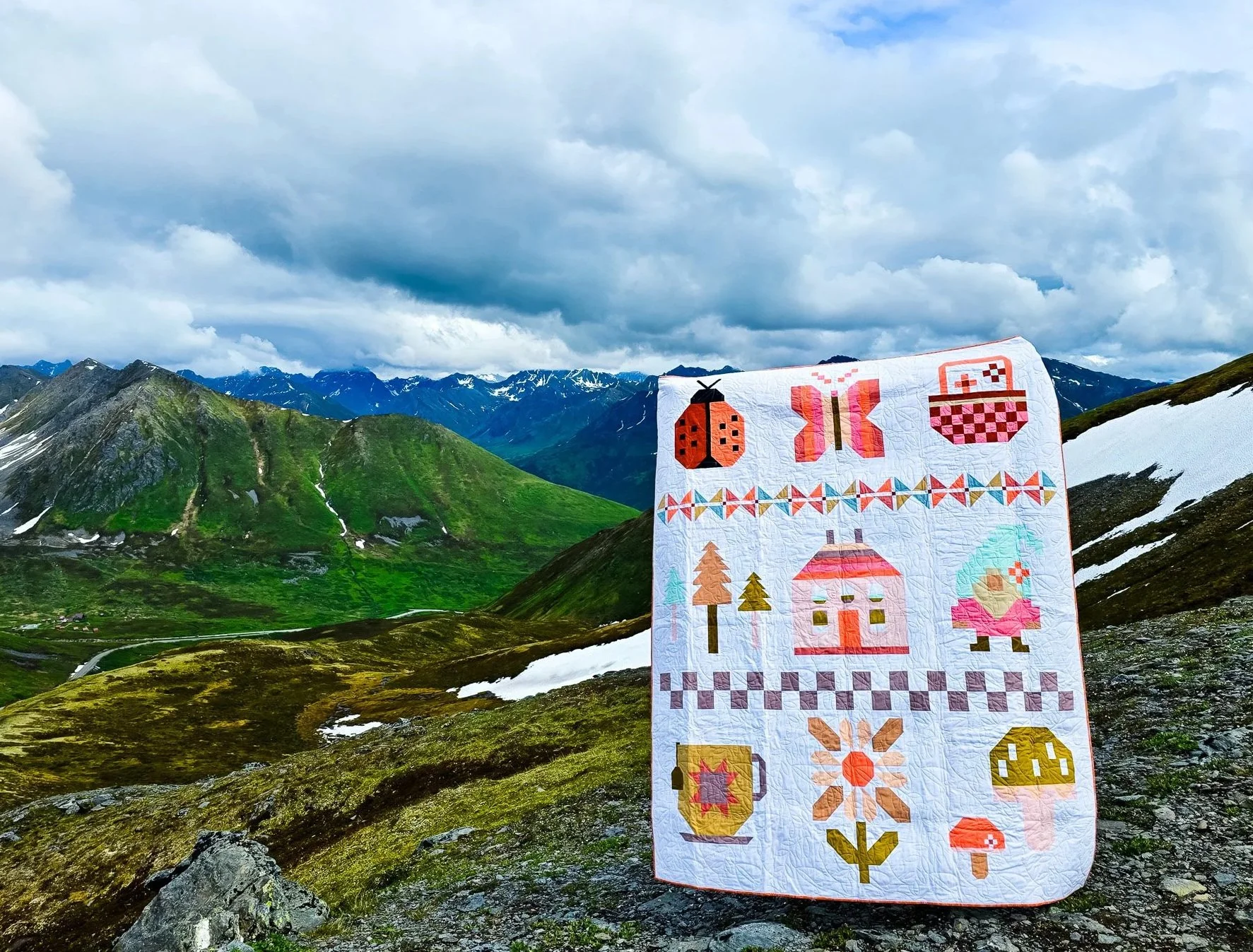 Finished Cottage Garden quilt displayed on a mountain overlook with scenic views in the background.