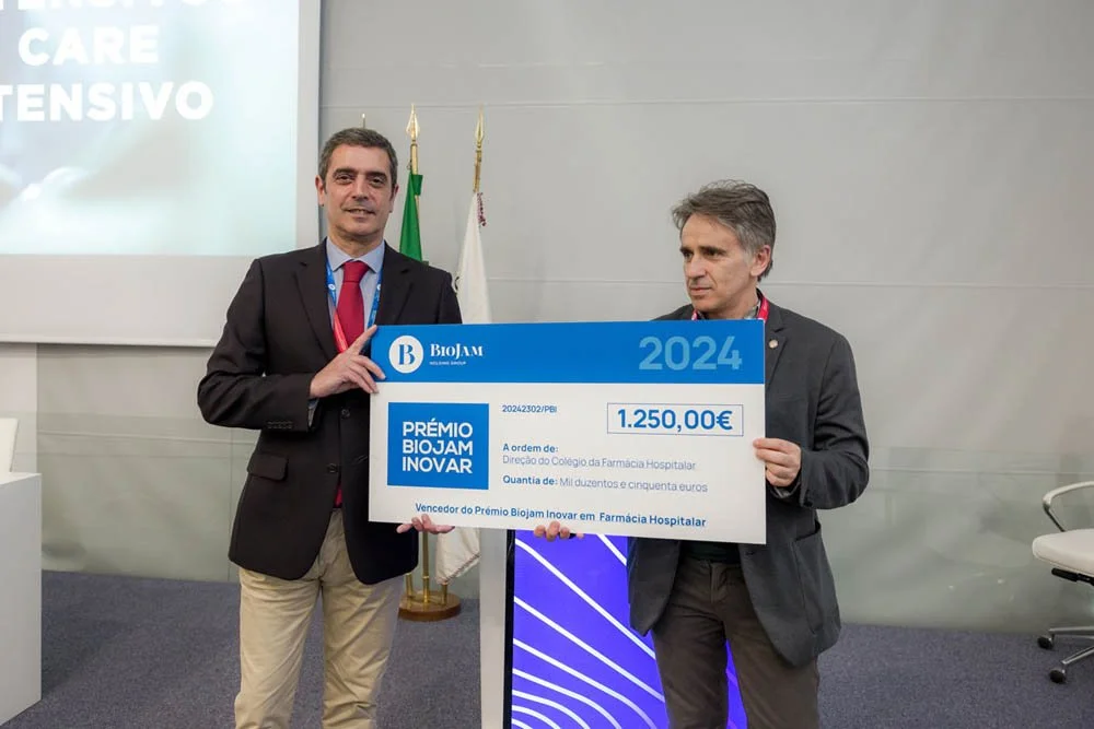 Dois homens segurando um cheque grande durante uma cerimônia de premiação em um ambiente interno.