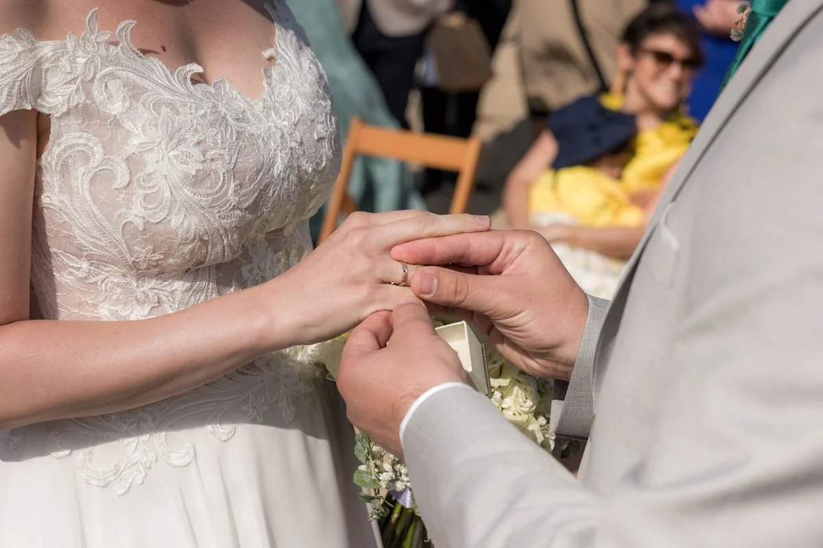 Casamento com troca de alianças entre noivos, com convidados ao fundo