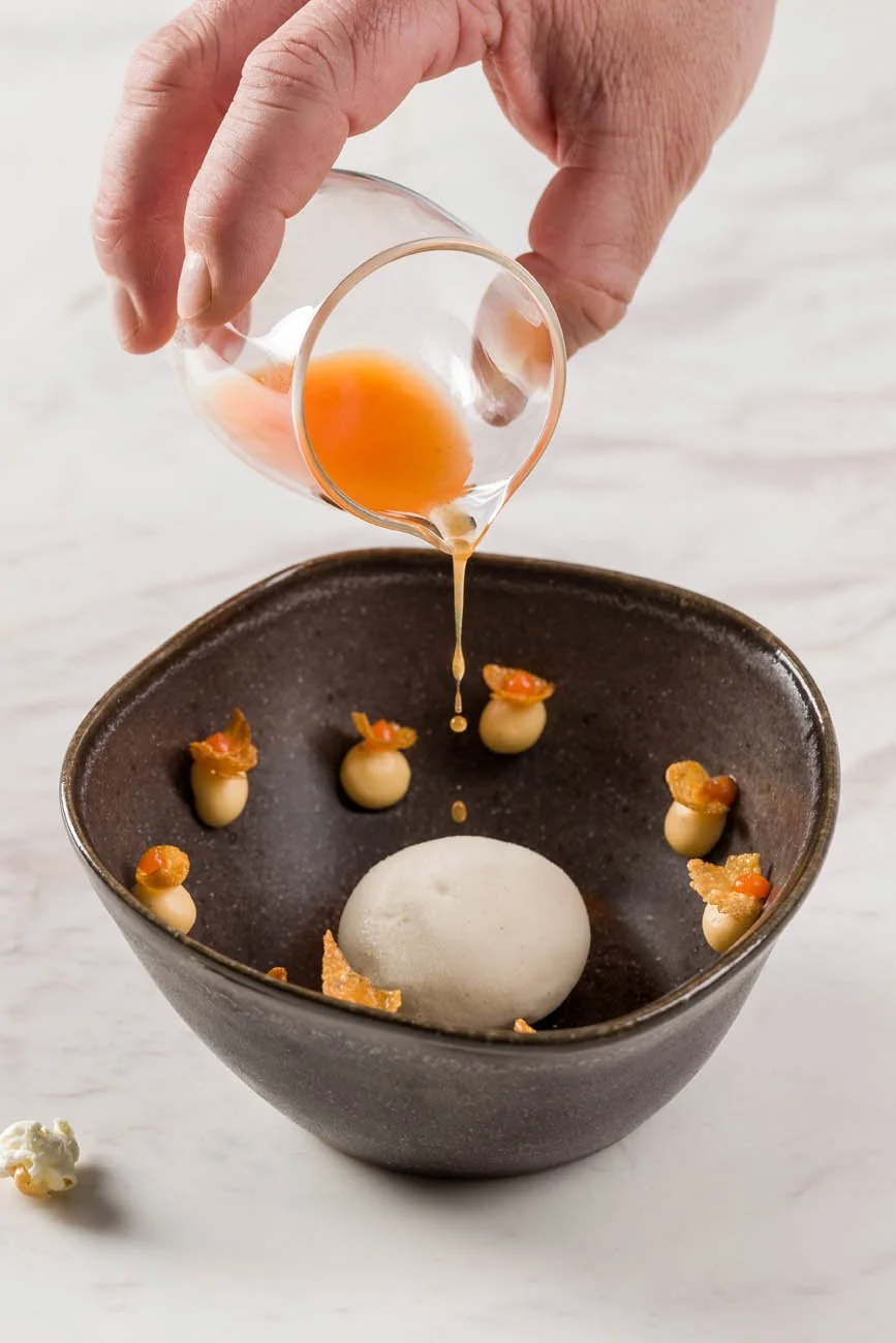 Pessoa adicionando ovo a uma preparação culinária, colocando ovos cozidos decorados com pedaços de pimenta dentro de uma tigela preta