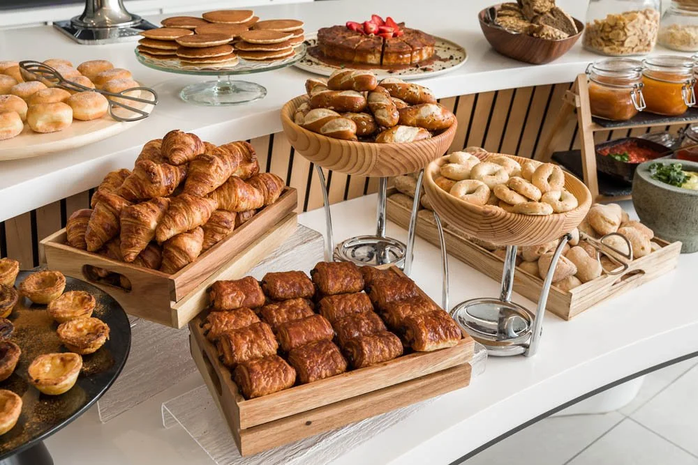 Mesa de café da manhã com croissants, pães, biscoitos e geleias.