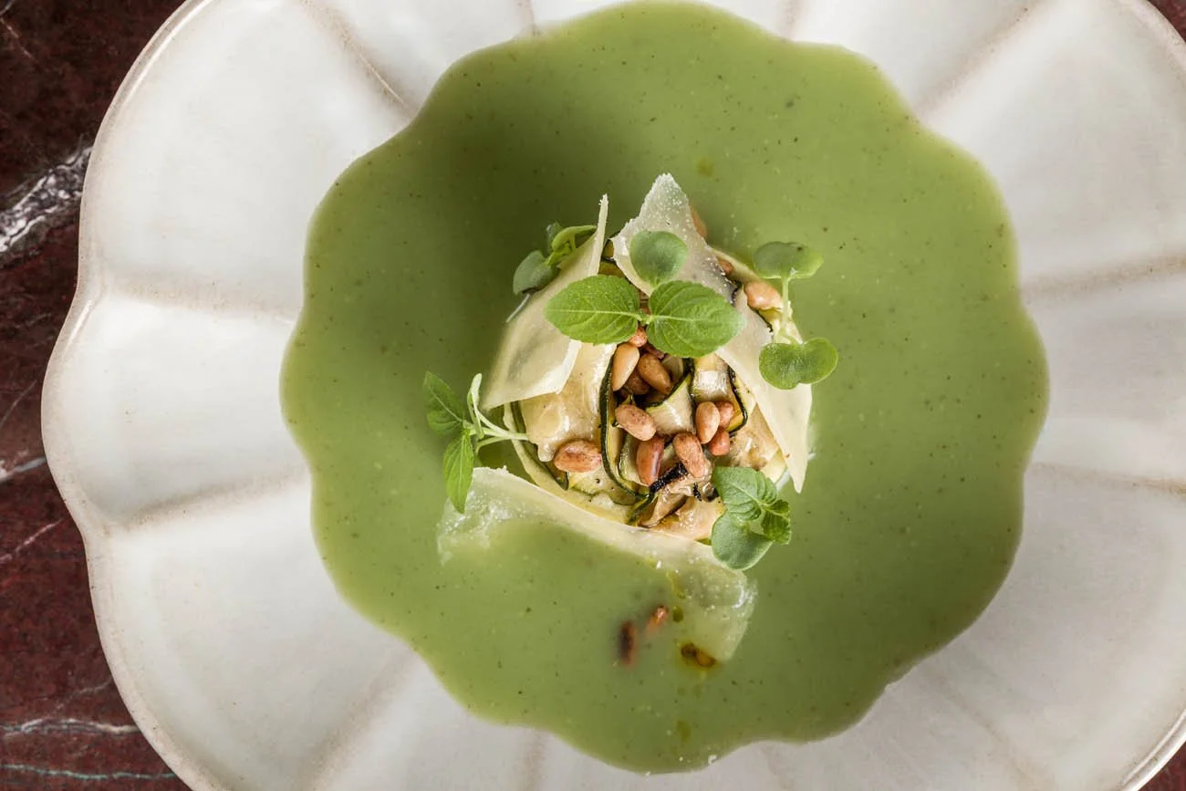 Prato de massa com molho verde, decorada com sementes e folhas de ervas.