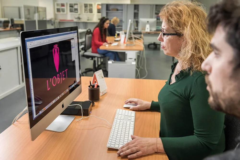 Mulher visualizando design gráfico no computador em ambiente de escritório compartilhado