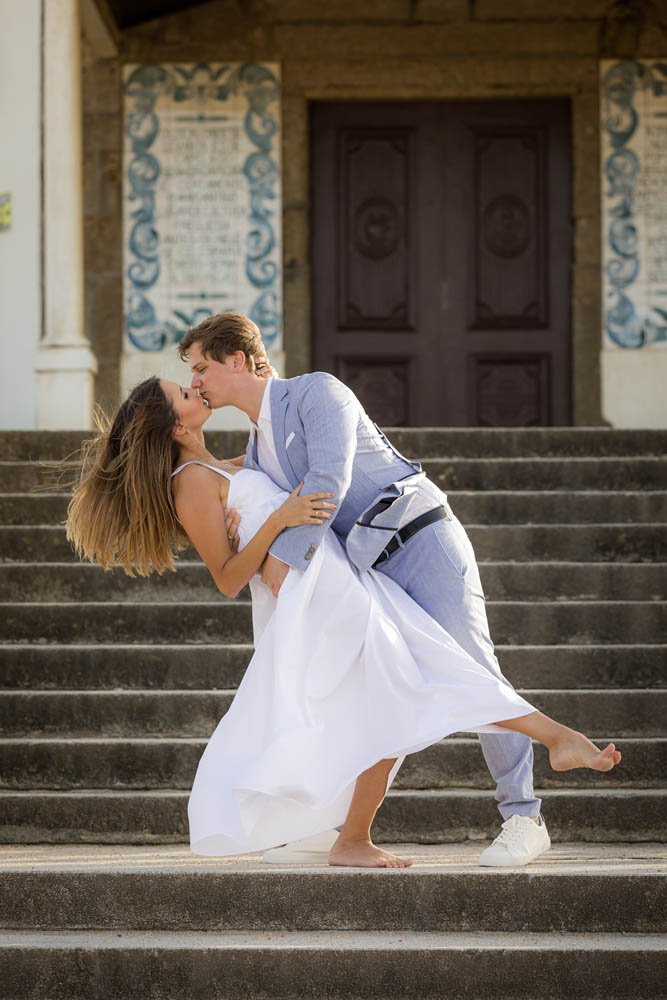 Casal apaixonado, o homem está segurando a mulher enquanto ela dança nos degraus de uma escada de pedra na frente de uma construção antiga.