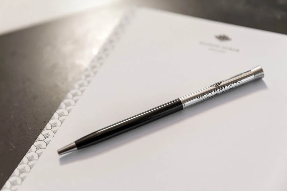 Caneta prateada e preta sobre uma folha de papel A4.