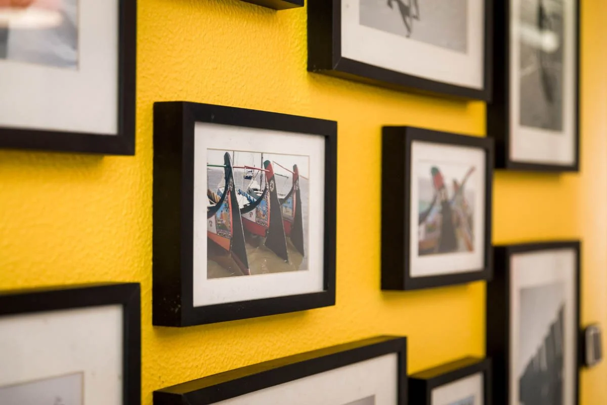 Quadro de fotos de barcos tradicionais de madeira com vela preta na parede amarela