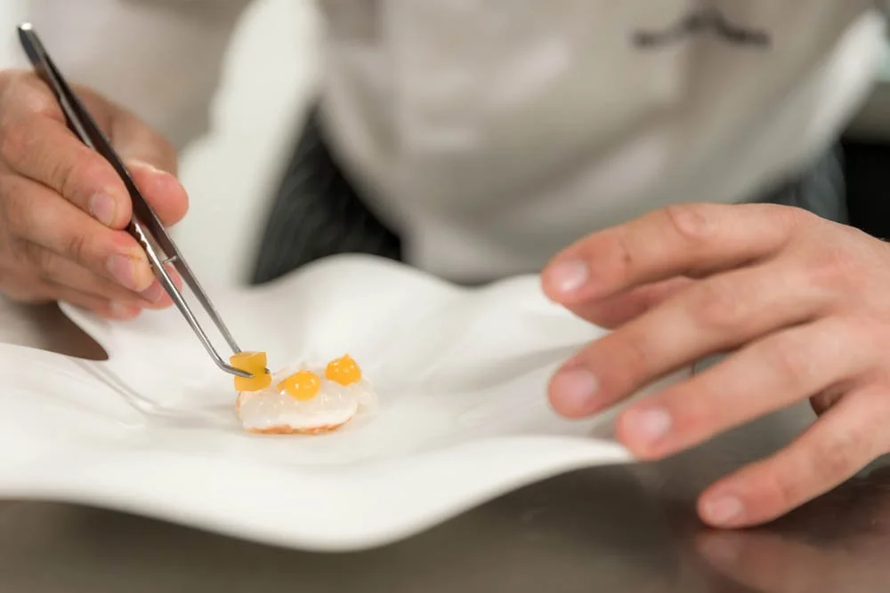 Chef decorando um prato com ovos cozidos cortados em pedaços pequenos.