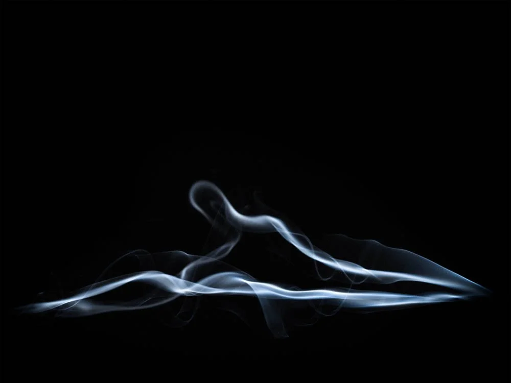 Fumaça branca contra fundo preto, com formas onduladas e delicadas.