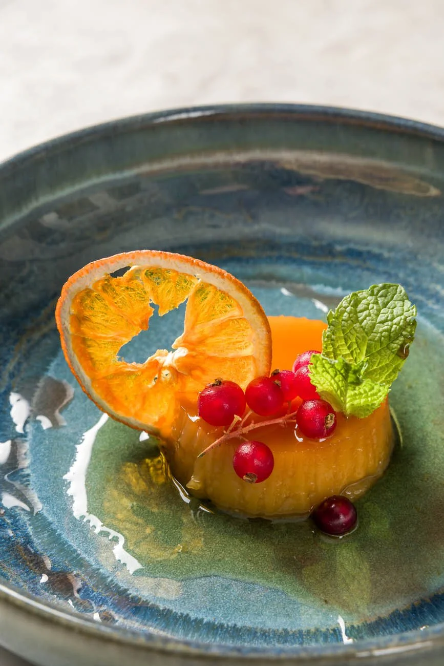 Sobremesa com fatia de fruta enfeitada com hortelã e cerejas.