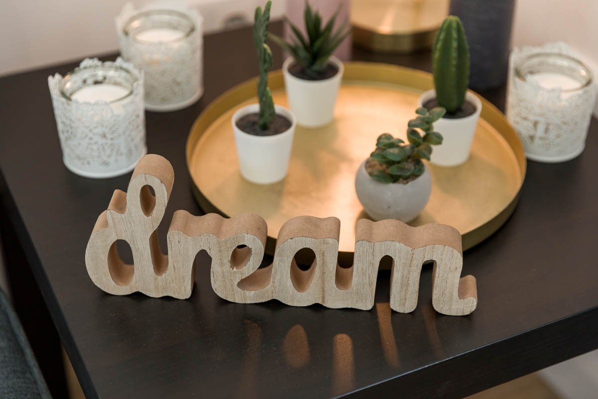 Decoração de mesa com vasos de plantas suculentas, velas e uma placa de madeira que diz 'dream'.