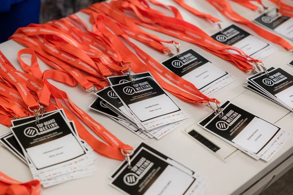 Cartões de identificação para uma conferência, cada um com uma fita laranja e o título 'Top Board Meeting'.