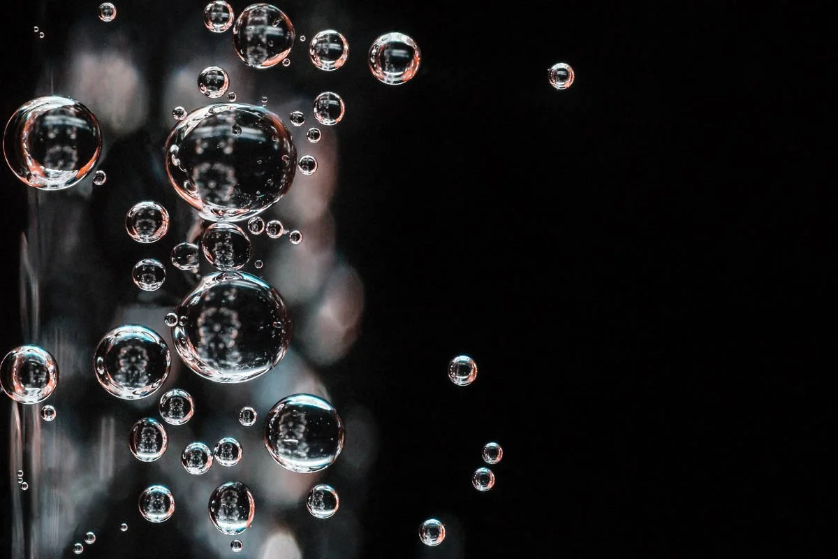 Bolhas de água suspensas no ar com fundo escuro.