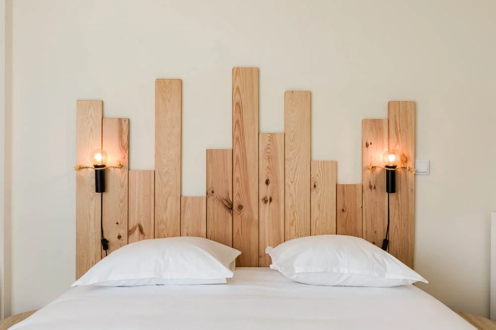 Cama com cabeceira de madeira com luzes embutidas nas extremidades.