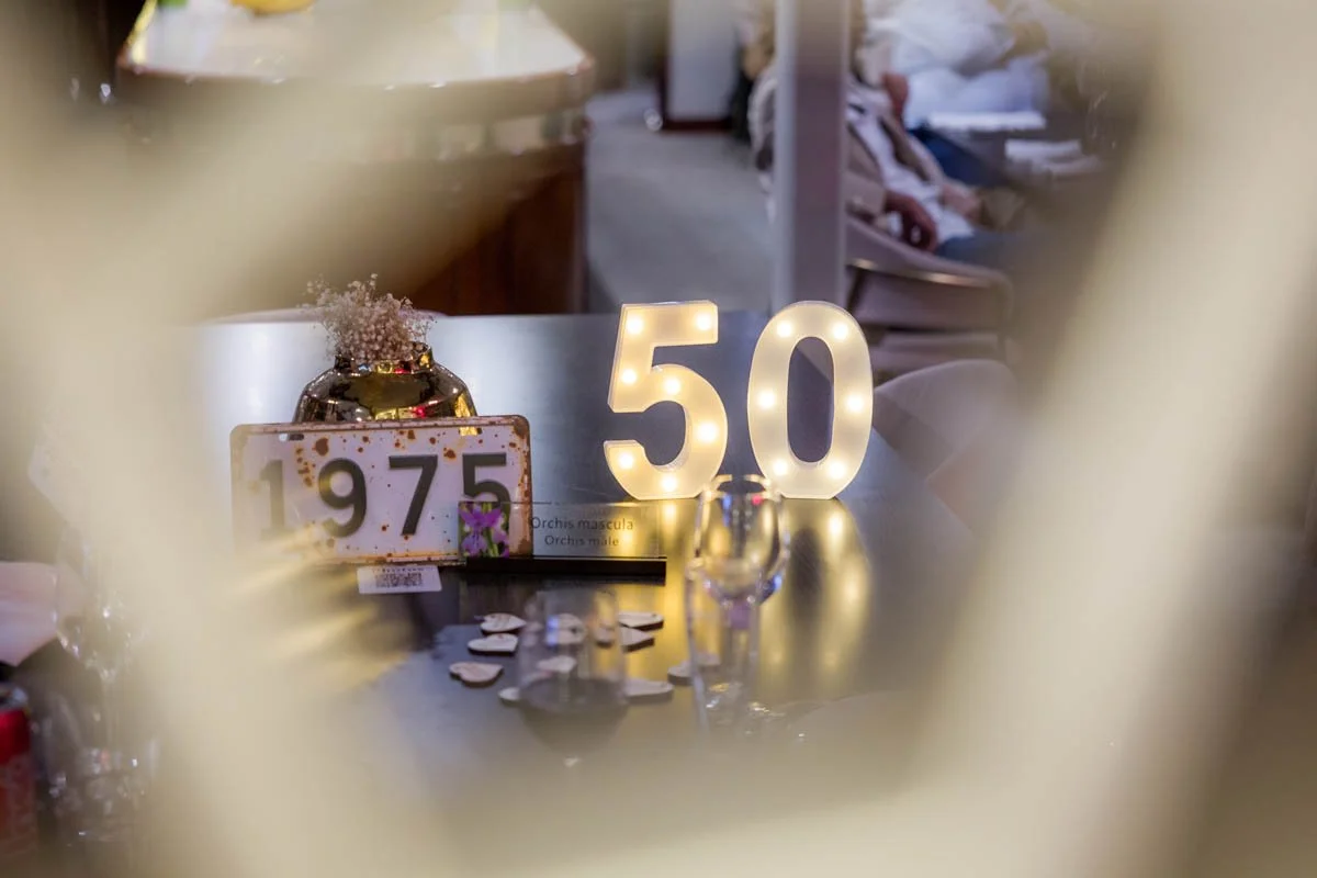 Decoração de aniversário de 50 anos com luminária em forma de número 50 e outros elementos decorativos.