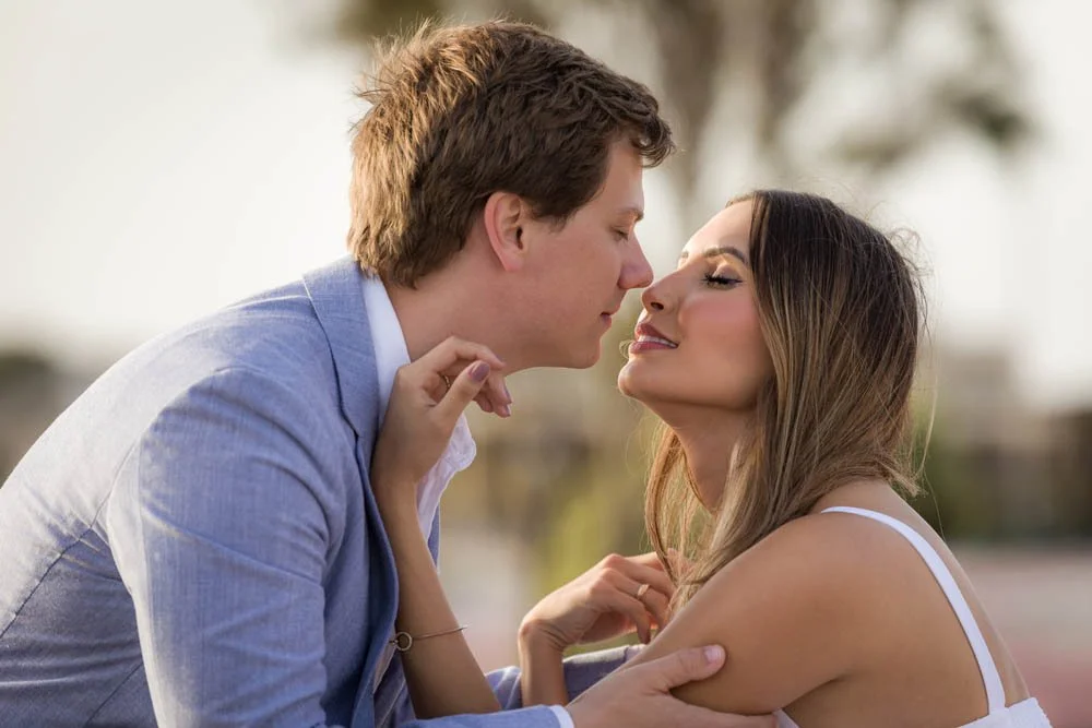 Casal se aproxima para um beijo, com expressão apaixonada ao ar livre.