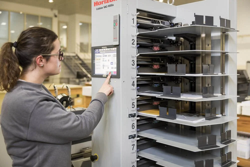 Mulher usando um painel de controle em uma máquina de classificação de papel na fábrica